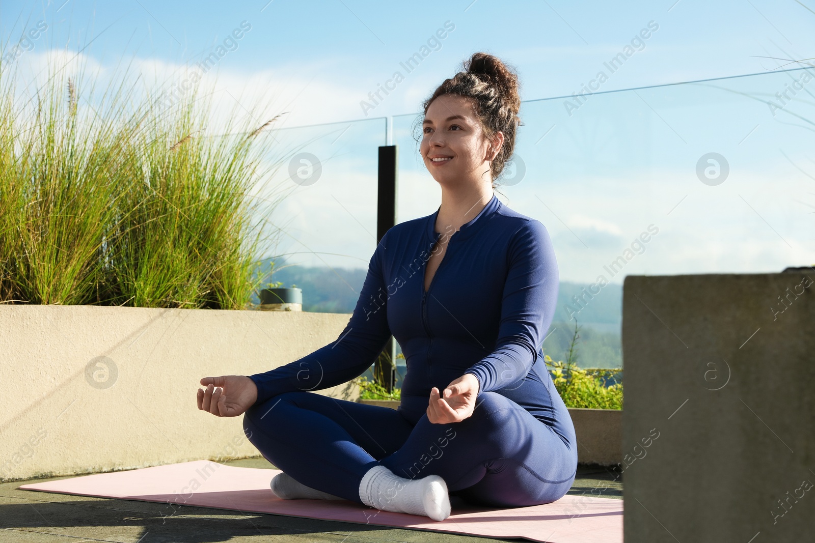Woman meditating on yoga mat at balcony Photo of Woman meditating on yoga mat at balcony