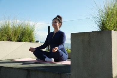 Photo of Woman meditating on yoga mat at balcony
