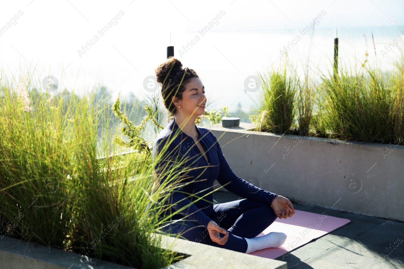 Woman meditating on yoga mat at balcony Photo of Woman meditating on yoga mat at balcony