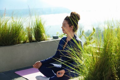 Photo of Woman meditating on yoga mat at balcony