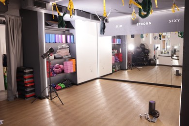 Photo of Different sports equipment, mirrors and aerial hammocks in fitness studio