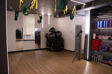 Photo of Different sports equipment, mirrors and aerial hammocks in fitness studio