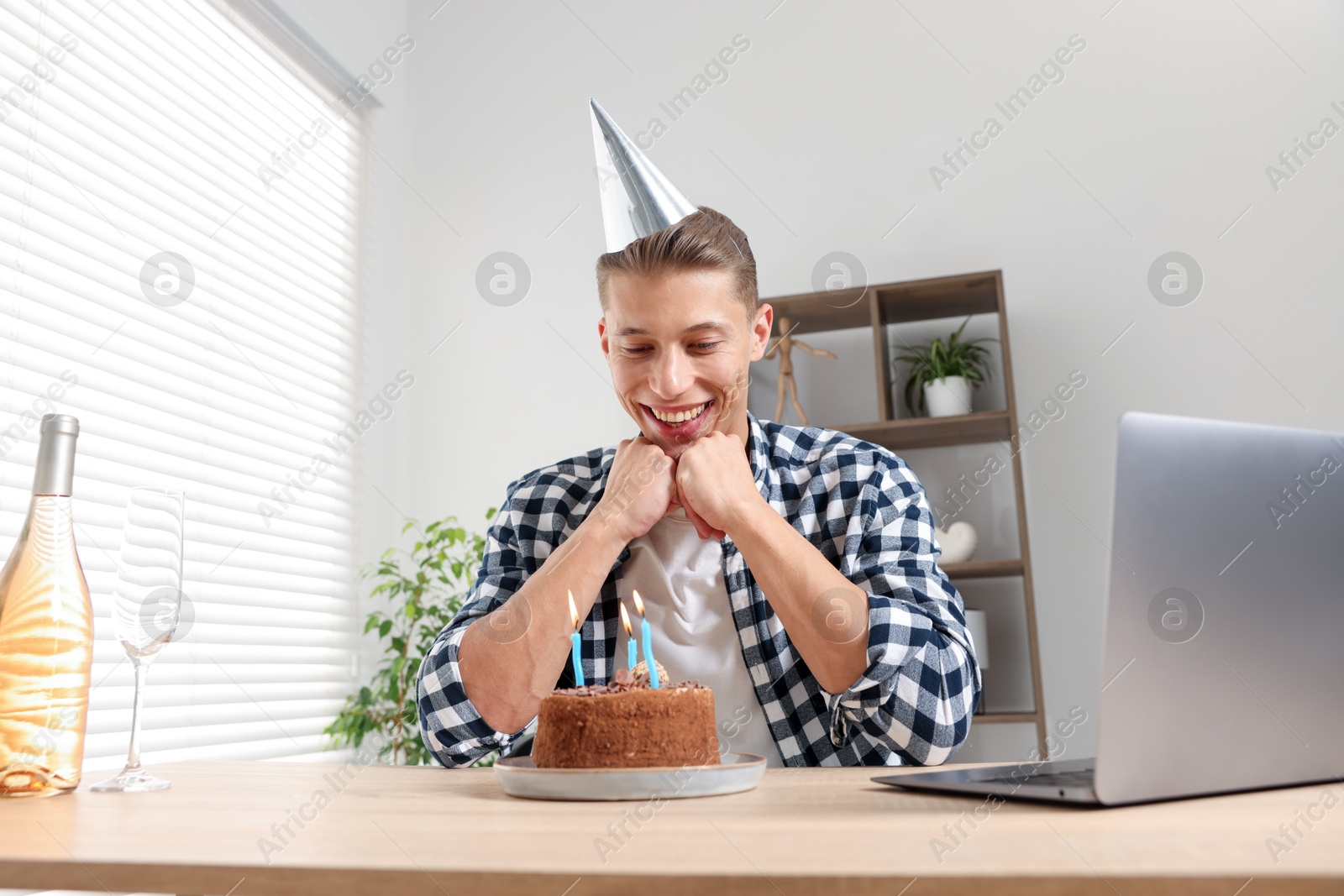 Birthday celebration. Man with cake having video call via laptop at desk indoors Photo of Birthday celebration. Man with cake having video call via laptop at desk indoors