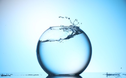 Photo of Glass aquarium with water on light blue background