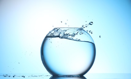 Photo of Glass aquarium with water on light blue background