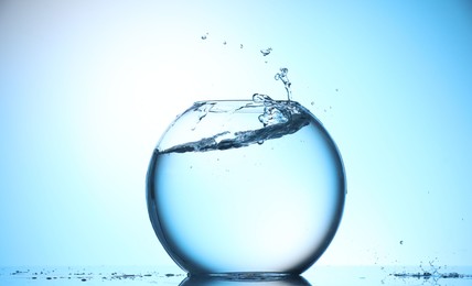 Photo of Glass aquarium with water on light blue background