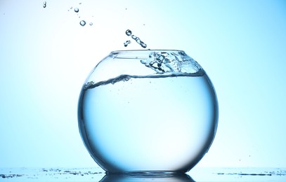 Photo of Glass aquarium with water on light blue background