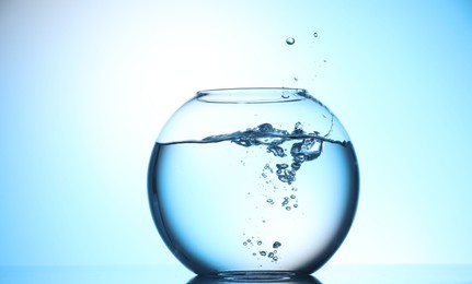 Photo of Glass aquarium with water on light blue background