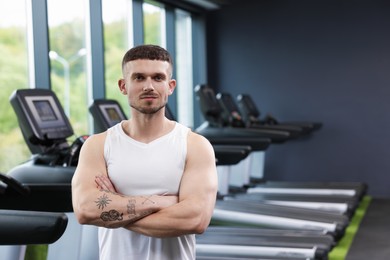 Photo of Portrait of professional personal trainer in sport center. Space for text