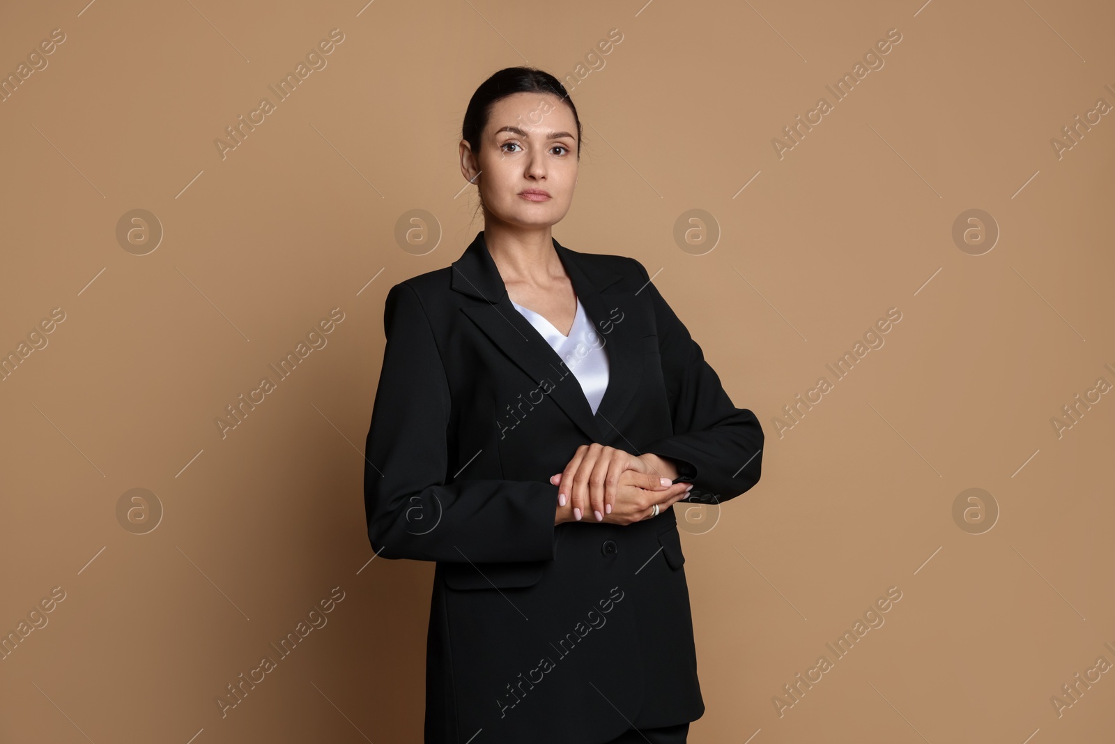 Confident business woman in suit on beige background Photo of Confident business woman in suit on beige background