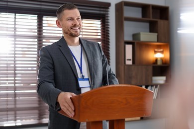 Photo of Man giving public speech with microphone at lectern indoors