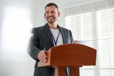 Photo of Man giving public speech with microphone at lectern indoors