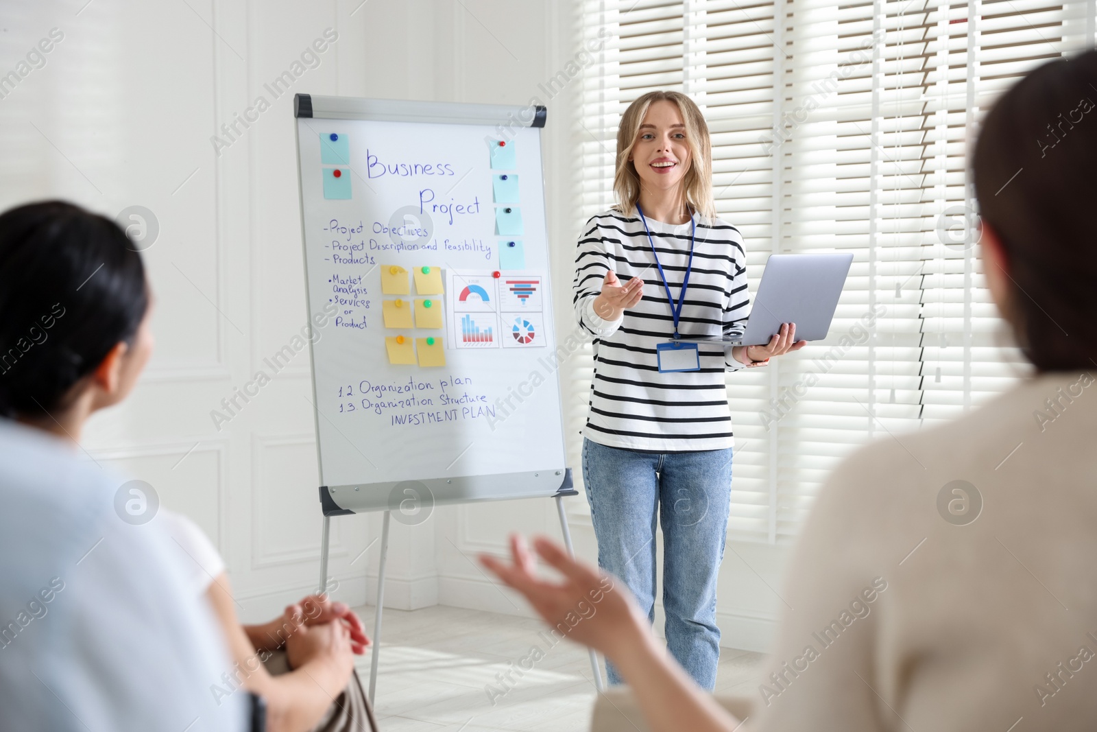 Woman giving public speech near whiteboard in front of audience indoors Photo of Woman giving public speech near whiteboard in front of audience indoors