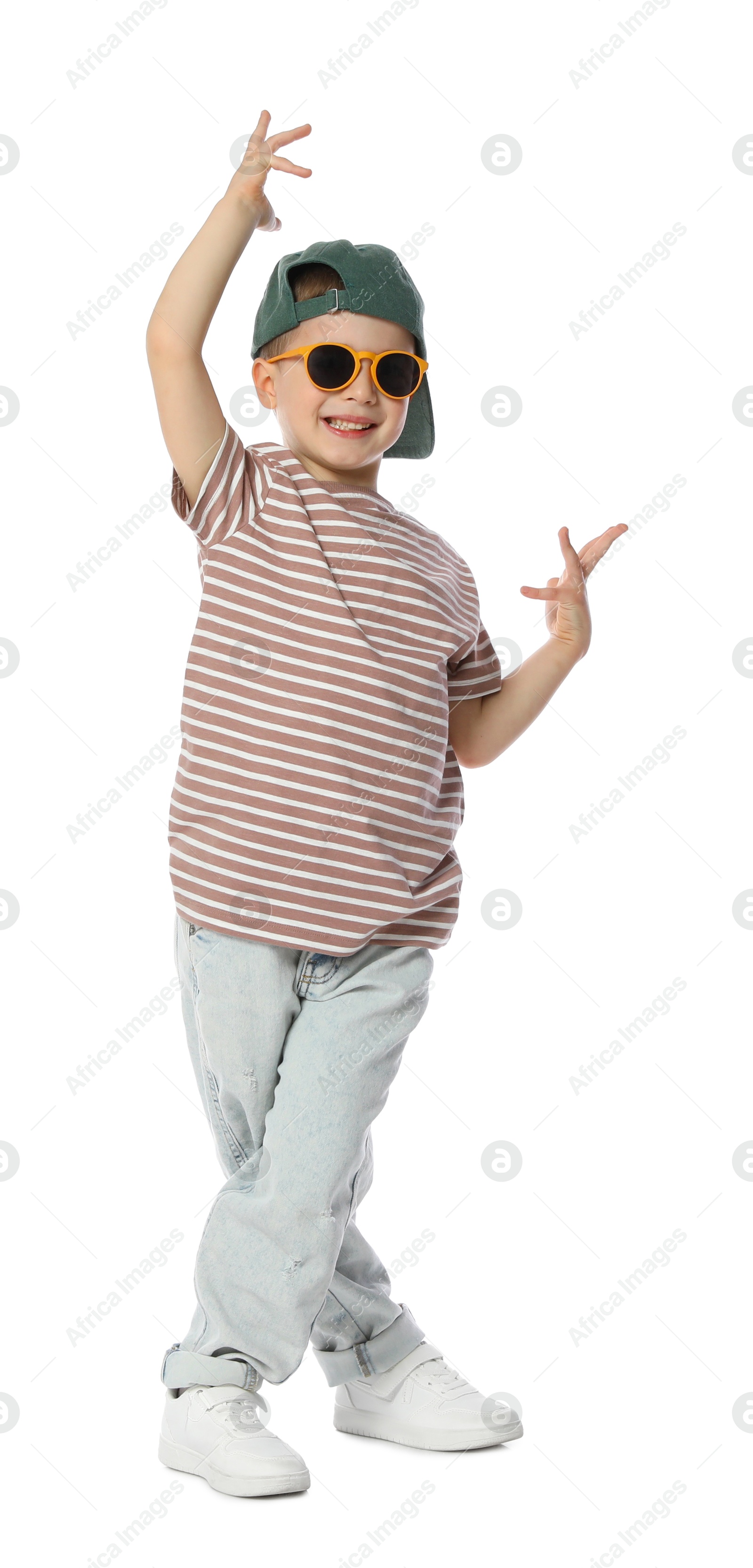 Photo of Happy little boy in sunglasses and baseball hat dancing on white background