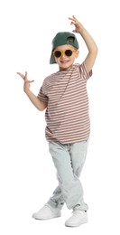 Photo of Happy little boy in sunglasses and baseball hat dancing on white background