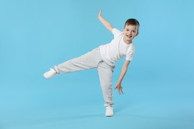 Photo of Happy little boy dancing on light blue background