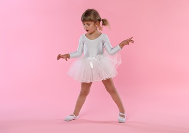 Photo of Cute little girl dancing on pink background