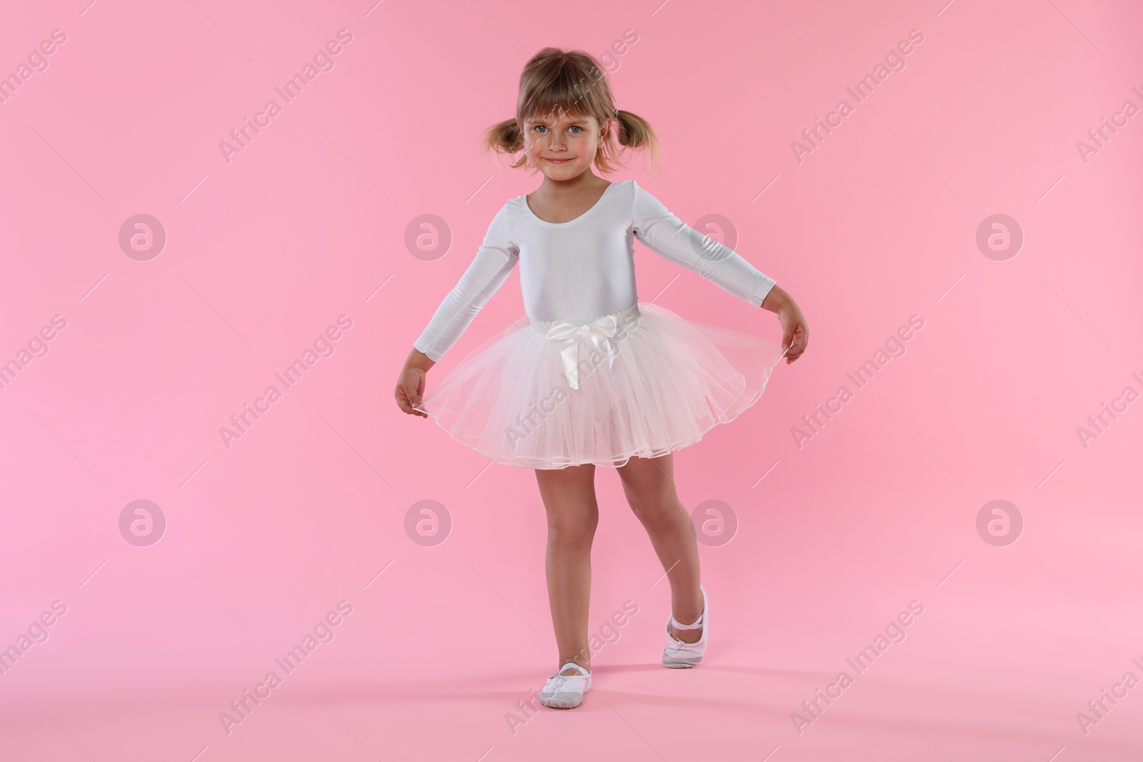 Cute little girl dancing on pink background Photo of Cute little girl dancing on pink background
