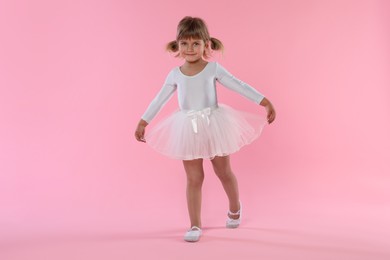Photo of Cute little girl dancing on pink background