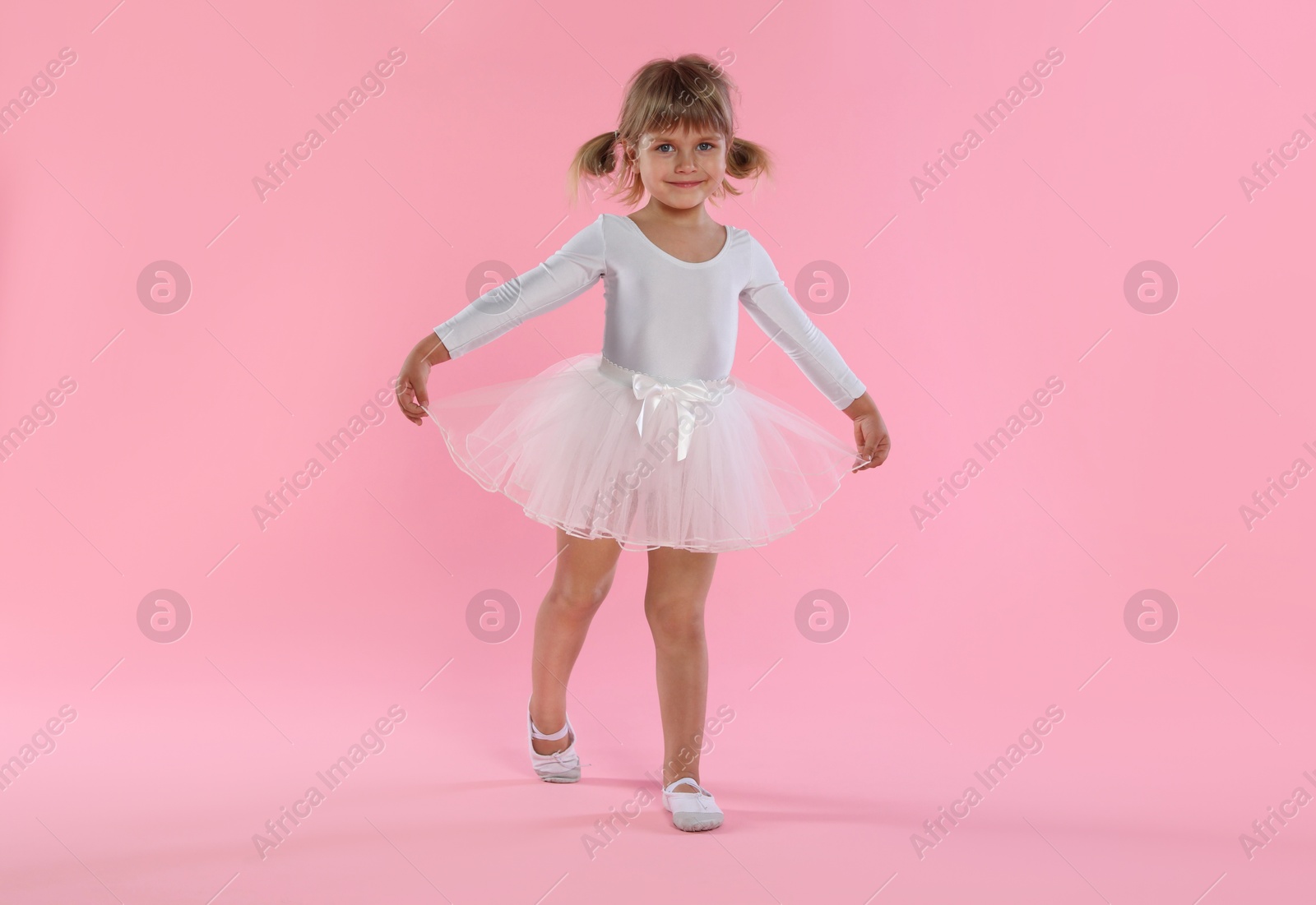 Cute little girl dancing on pink background Photo of Cute little girl dancing on pink background