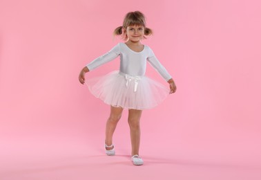 Photo of Cute little girl dancing on pink background