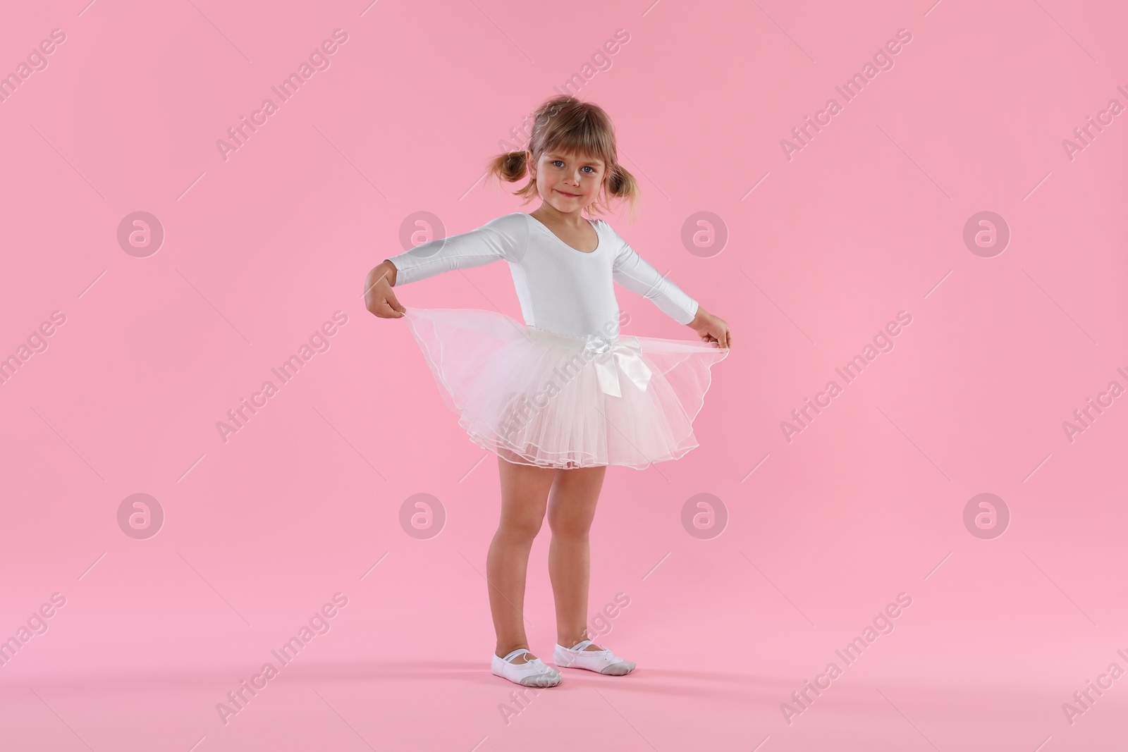 Cute little girl dancing on pink background Photo of Cute little girl dancing on pink background