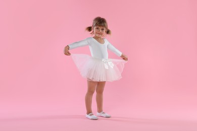 Photo of Cute little girl dancing on pink background