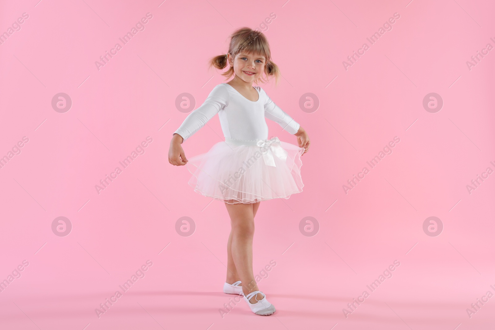 Cute little girl dancing on pink background Photo of Cute little girl dancing on pink background