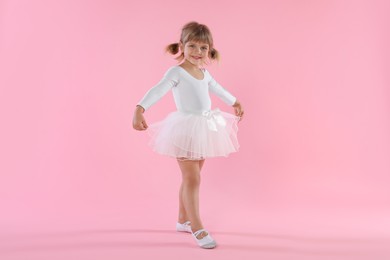 Photo of Cute little girl dancing on pink background