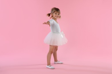Photo of Cute little girl dancing on pink background