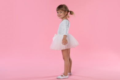 Photo of Cute little girl dancing on pink background