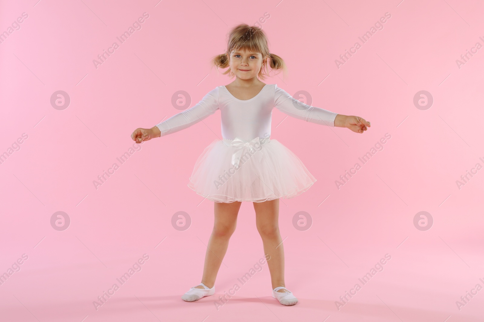 Cute little girl dancing on pink background Photo of Cute little girl dancing on pink background