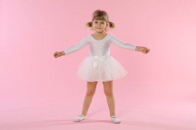Photo of Cute little girl dancing on pink background