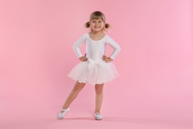 Photo of Cute little girl dancing on pink background