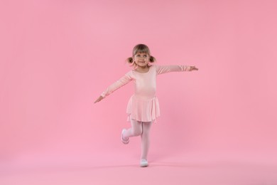 Photo of Cute little girl dancing on pink background
