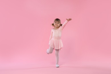 Photo of Cute little girl dancing on pink background