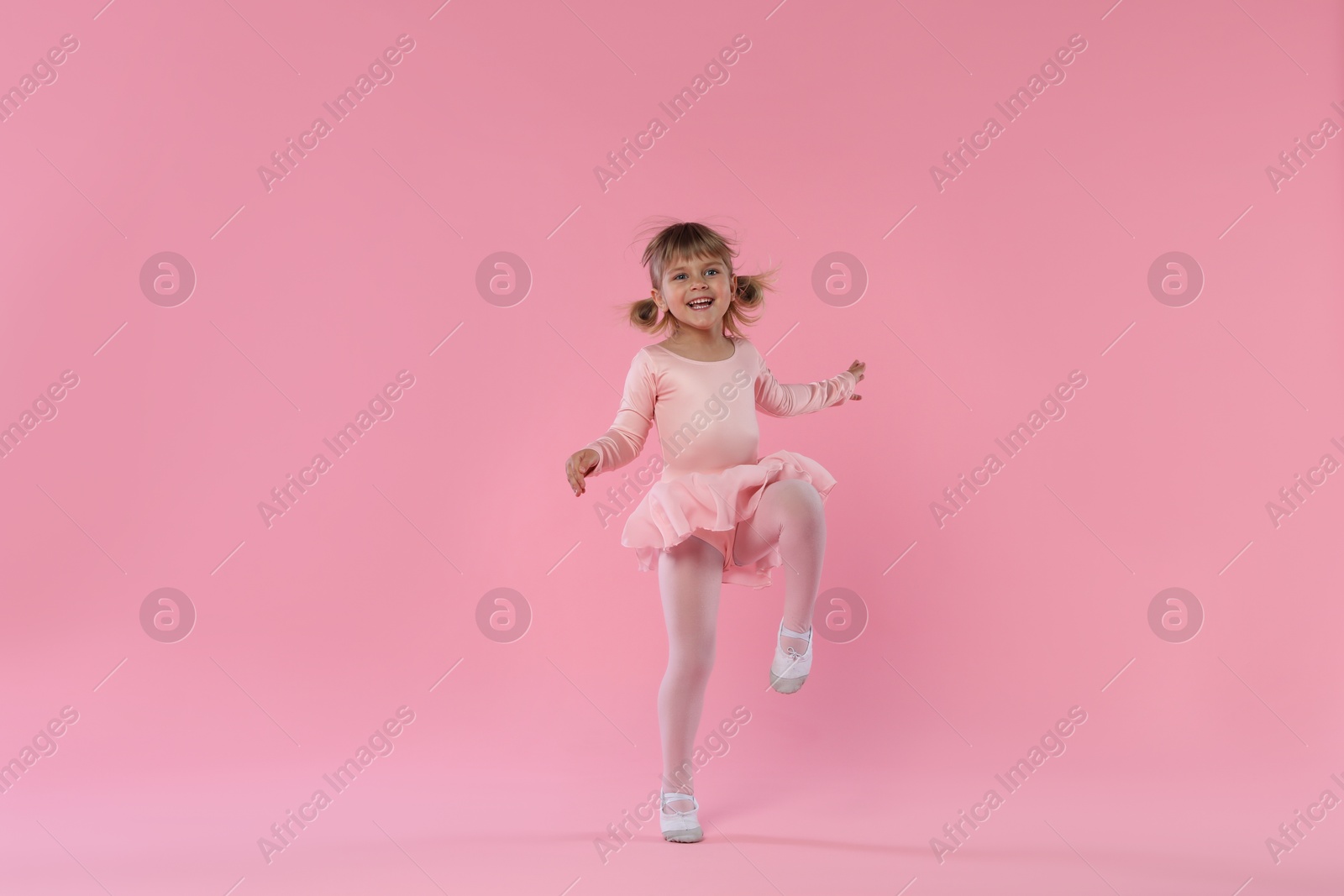 Cute little girl dancing on pink background Photo of Cute little girl dancing on pink background