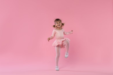 Photo of Cute little girl dancing on pink background