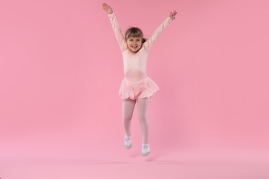 Photo of Cute little girl dancing on pink background
