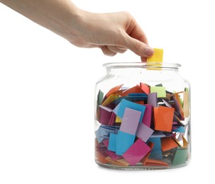 Photo of Woman taking color paper piece form glass jar on white background, closeup