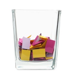 Photo of Colorful paper pieces in glass holder isolated on white