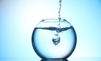 Photo of Glass aquarium with water on light blue background
