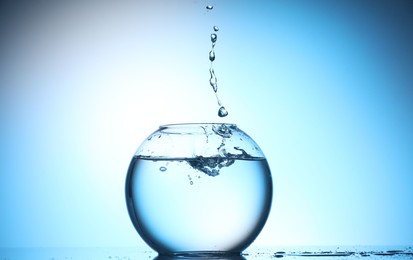 Photo of Glass aquarium with water on light blue background
