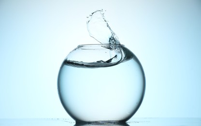 Photo of Glass aquarium with water on light blue background