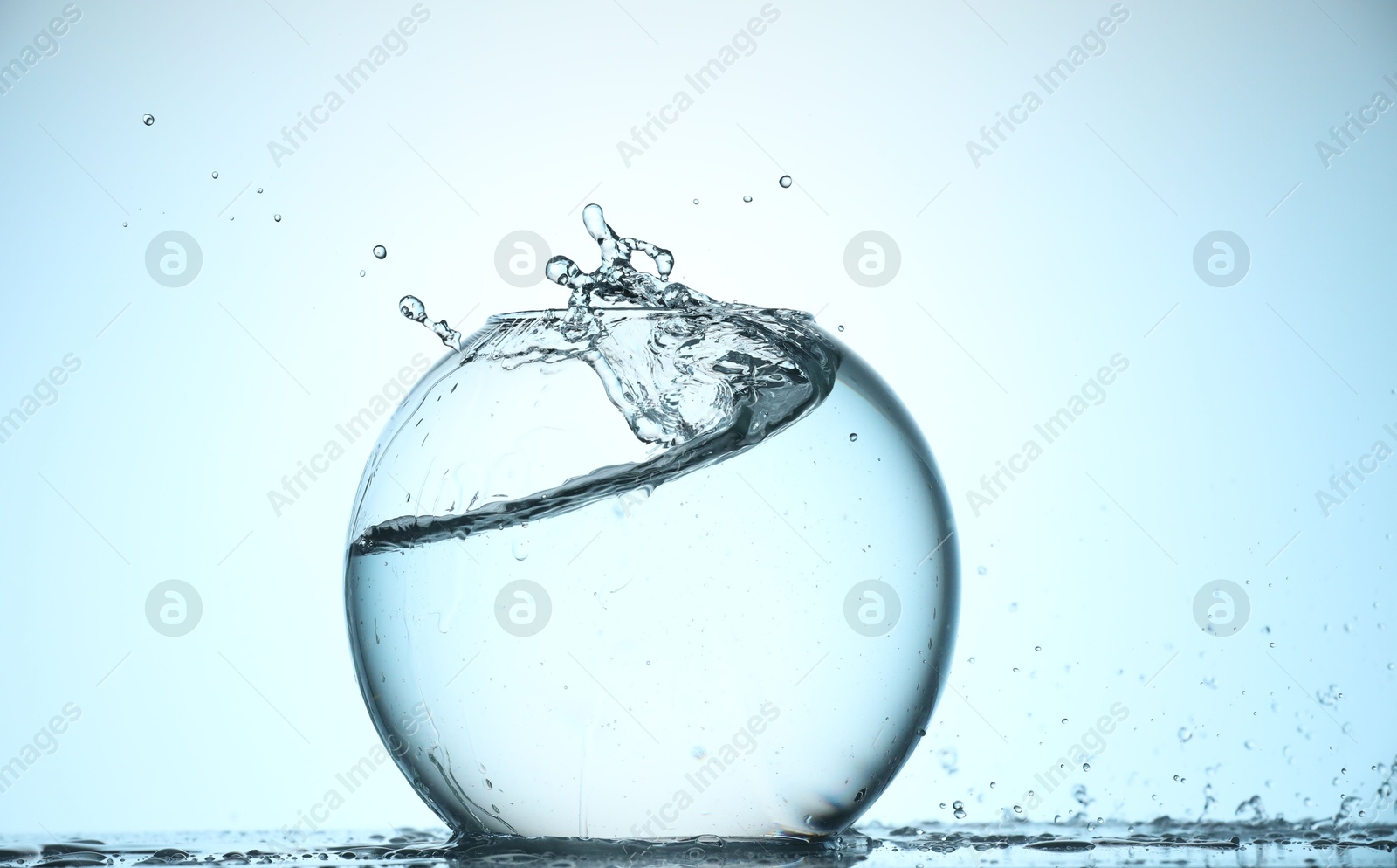 Glass aquarium with water on light blue background Photo of Glass aquarium with water on light blue background