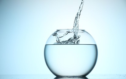 Photo of Glass aquarium with water on light blue background