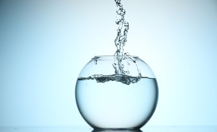 Photo of Glass aquarium with water on light blue background