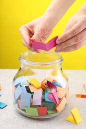 Photo of Woman taking paper with message out of jar at light table, closeup