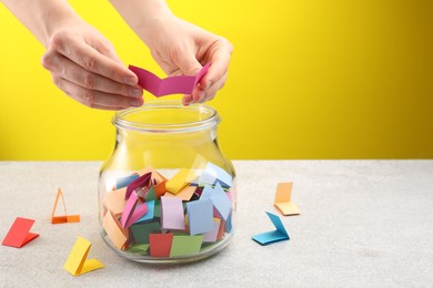 Photo of Woman taking paper with message out of jar at light table, closeup. Space for text