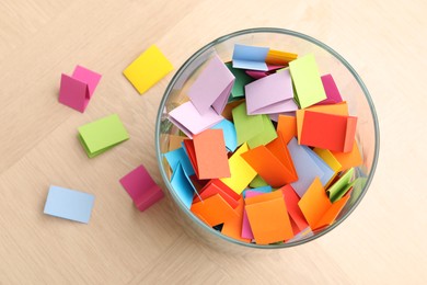 Photo of Jar with colorful pieces of paper on wooden table, top view